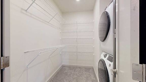 An oversized walk-in closet with wire shelving and a stacked washer and dryer.