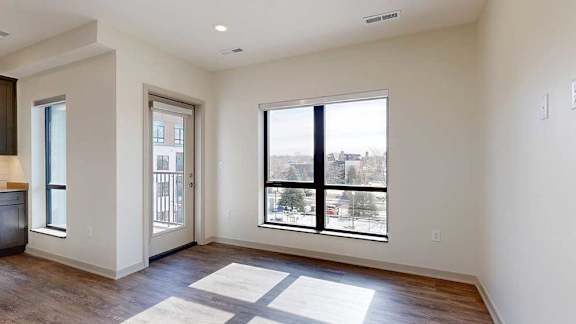 A living room with hardwood-style flooring and a floor-to-ceiling window.