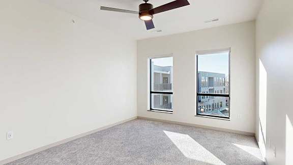 a bedroom with a ceiling fan and two windows