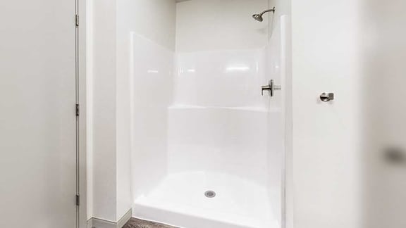 a white walk-in shower with some built-in shelving