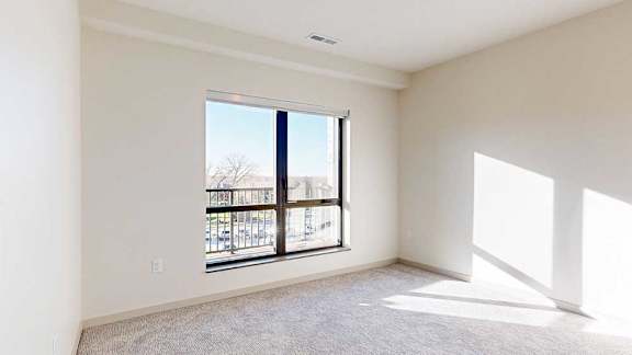 a bedroom with carpeted flooring and a large window for natural light
