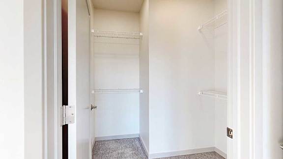 an L-shaped walk-in closet with built-in wire shelving and hanging space