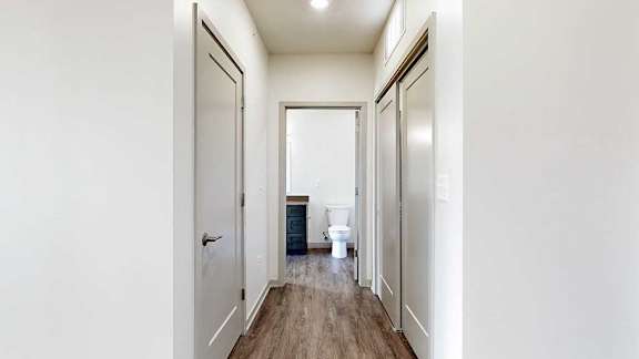 a hallway with an entry closet, a laundry closet, and a door to a bathroom
