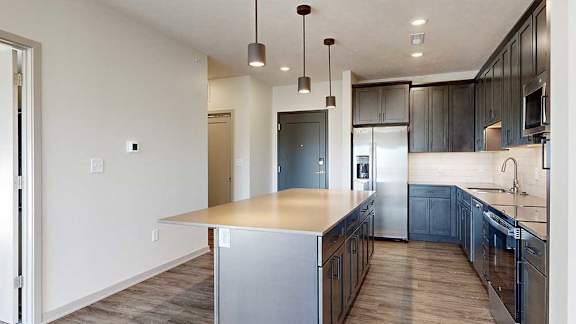 a kitchen with a large central island with dark wooden cabinets and stainless steel appliances