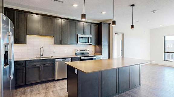 a modern kitchen with dark wood cabinets and stainless steel appliances