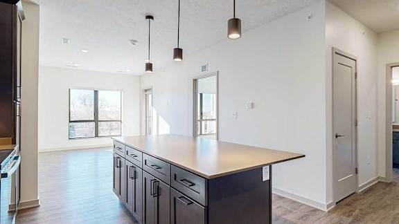a kitchen with a large island and a living room with a window and a door to a bedroom