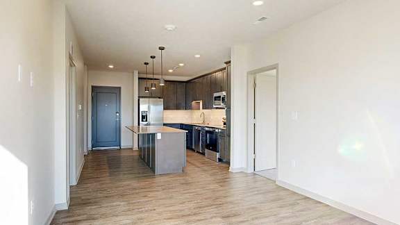 a living room with hardwood flooring and a kitchen with dark wood cabinets
