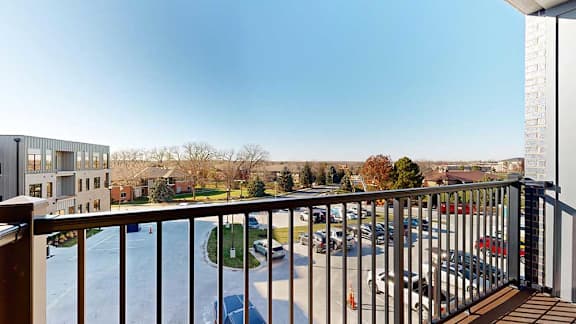 a balcony with a metal railing and surrounding parking area