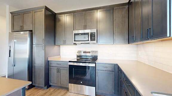 A close up of the stainless steel microwave and range in a kitchen with dark wooden cabinets.