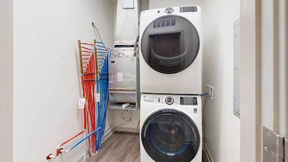 A stacked full-sized washer and dryer in a laundry room.