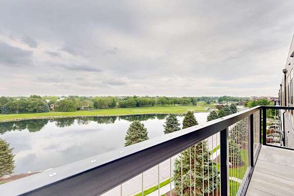 An oversized balcony with a metal railing overlooking the neighboring pond.