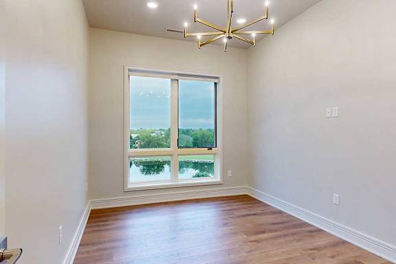 A dining room with a floor-to-ceiling window, a metal chandelier, and hardwood flooring.