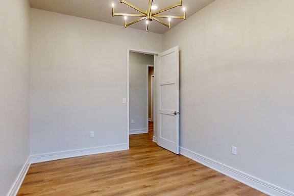 A separate dining room with a metal chandelier and hardwood flooring.