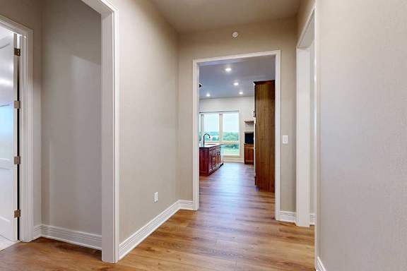 An entry hallway with a door on the left and a kitchen in the distance.