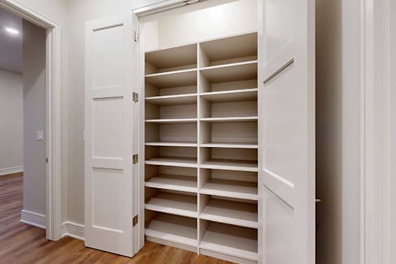 A hallway closet with several built-in shelves.