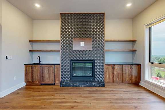 A modern living room with a fire place with a custom floor-to-ceiling panel, and built-in cabinetry and shelves on either side.