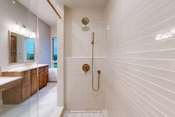 A tiled walk-in shower with a sliding glass door, and a shower head with detached sprayer.