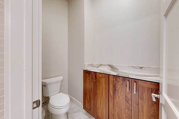 A bathroom with a private lavatory with built-in cabinet and quartz countertop.