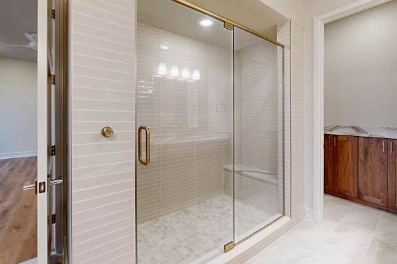 A tiled walk-in shower with a glass door and a built-in bench.