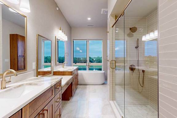 A spacious ensuite bathroom with a double vanity sink, walk-in shower, soaking tub, and attached dressing room.