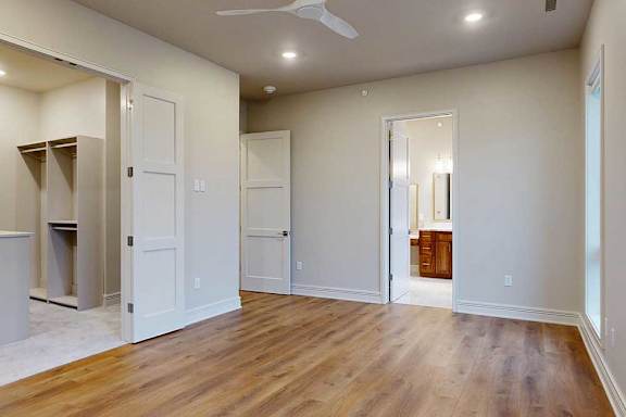 A bedroom with hardwood flooring, a walk-in boutique closet, and ensuite bathroom.