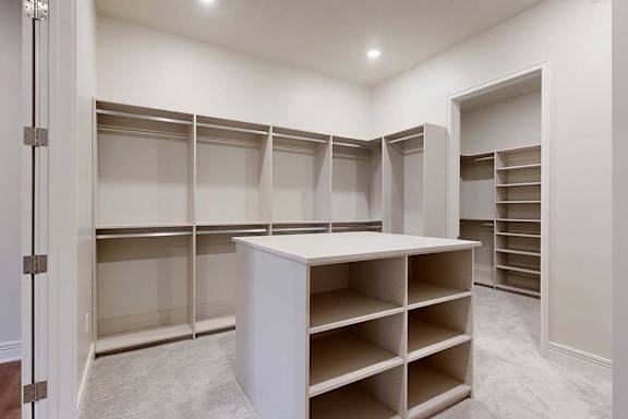 An oversized, boutique-style walk-in closet with built-in drawers and shelves.