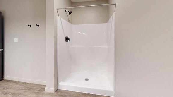 A bathroom with a walk-in shower with black fixtures.
