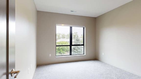 A carpeted bedroom with a floor-to-ceiling window.