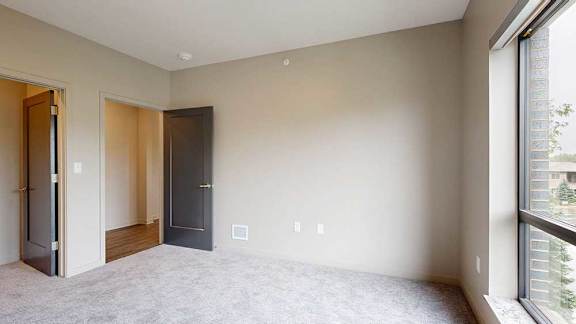 A bedroom with a floor-to-ceiling window and a walk-in closet.