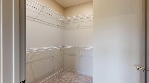 An L-shaped walk-in closet with several built-in shelves.