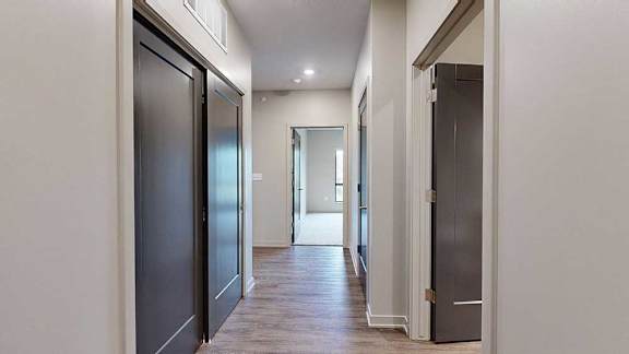 A hallway with a closet to the side, and an open door to a bedroom at the end.
