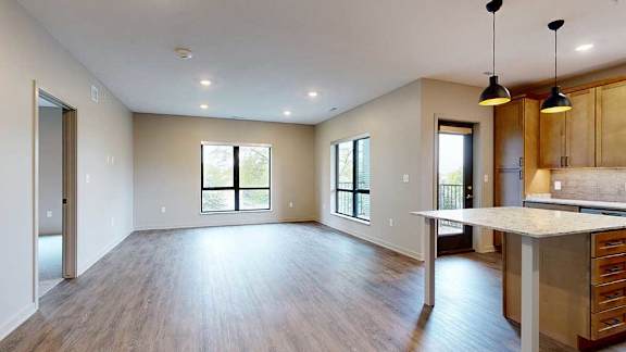 A living room with hardwood-style flooring and floor-to-ceiling windows.