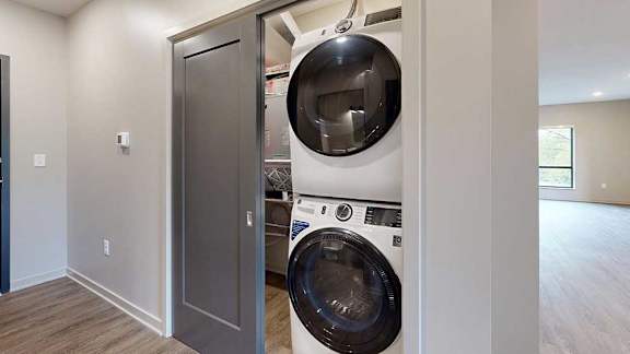 A stacked full-sized washer and dryer in a laundry room.