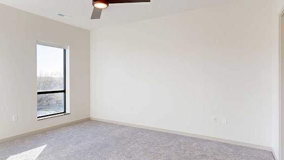 a bedroom with a carpeted floor, a ceiling fan, and large window
