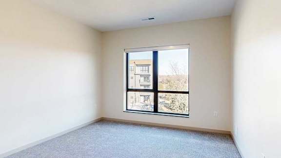 a bedroom with a carpeted floor and a large window looking out to the courtyard