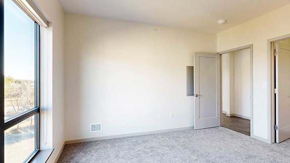 a bedroom with a carpeted floor, a large window, and a spacious walk-in closet