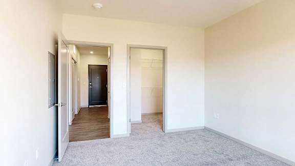 A spacious room with a carpeted floor and white walls.