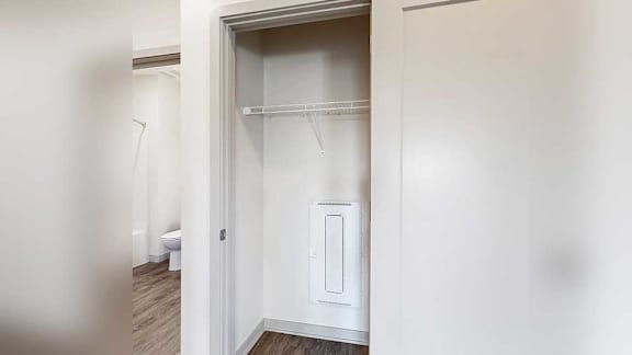a hallway coat closet with a built-in wire shelf