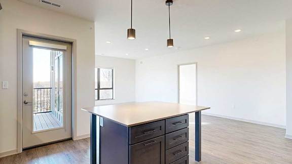 a kitchen with a large central island with storage, and a door to the balcony