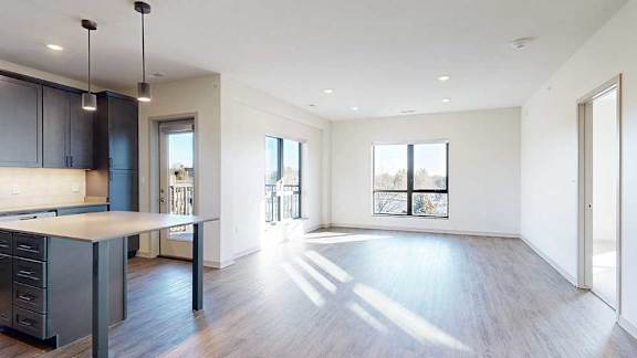 a spacious living room with large windows and a modern kitchen with dark wooden cabinets