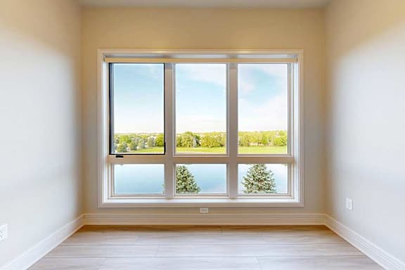 A room with a large window overlooking a body of water and trees.