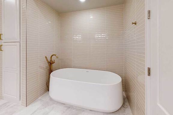 Free standing soaking tub in nook with tiled surround in a penthouse apartment