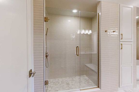 Tiled walk-in shower with glass door and gold fhardware