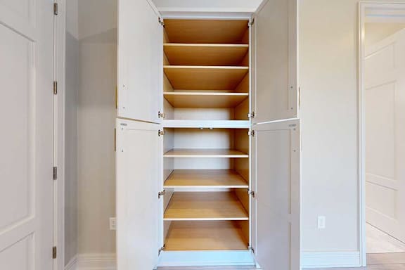 A white cabinet with shelves in a walk-in closet