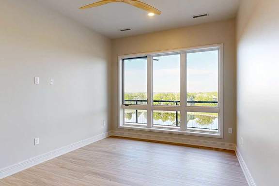 A bedroom with a large window and wooden flooring.