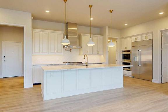 A kitchen with a white island and stainless steel appliances.