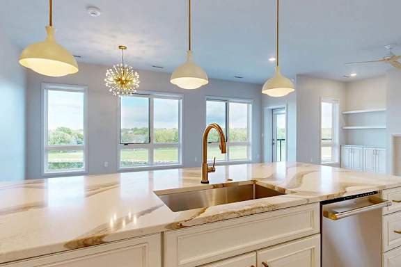 A kitchen with a marble countertop and a large windows.
