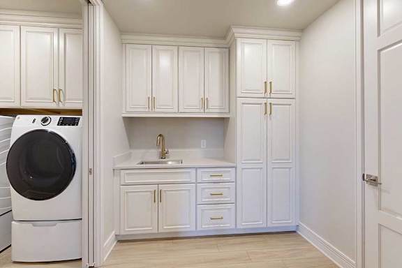 Laundry room with tons of built in cabinets for storage, a sink, and front loading machines