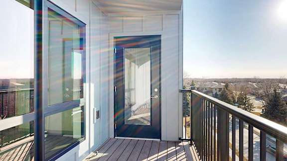 a balcony with a windowed door leading to the living room and a window from a bedroom