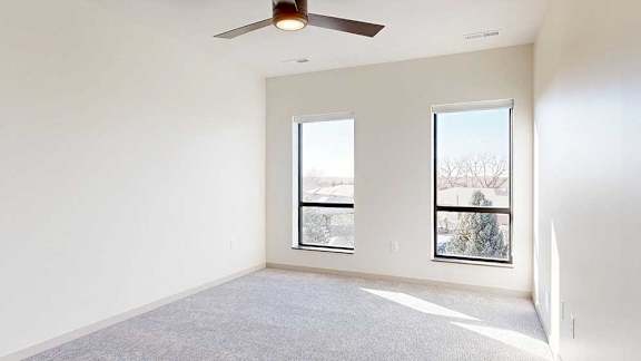 a bedroom with two tall windows and a ceiling fan